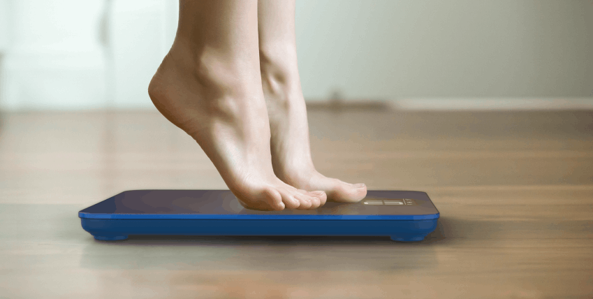 Feet tiptoeing on weighing scales
